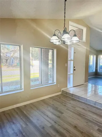 a view of an empty room with wooden floor and windows