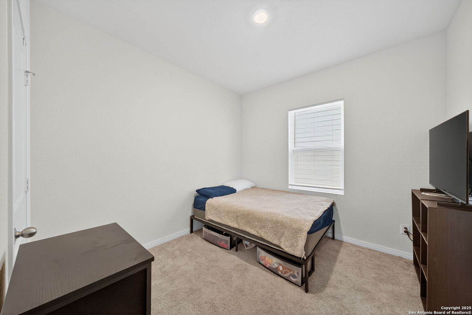 7710 Fern Hollow San Antonio, TX 78252 - Photo 17 of 26 a bedroom with a bed and a flat tv screen on a dresser