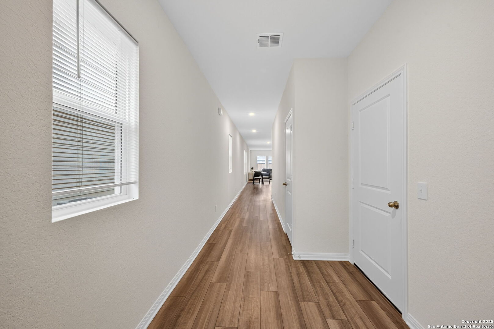 7710 Fern Hollow San Antonio, TX 78252 - Photo 3 of 26 a view of a room with wooden floor a ceiling fan and windows