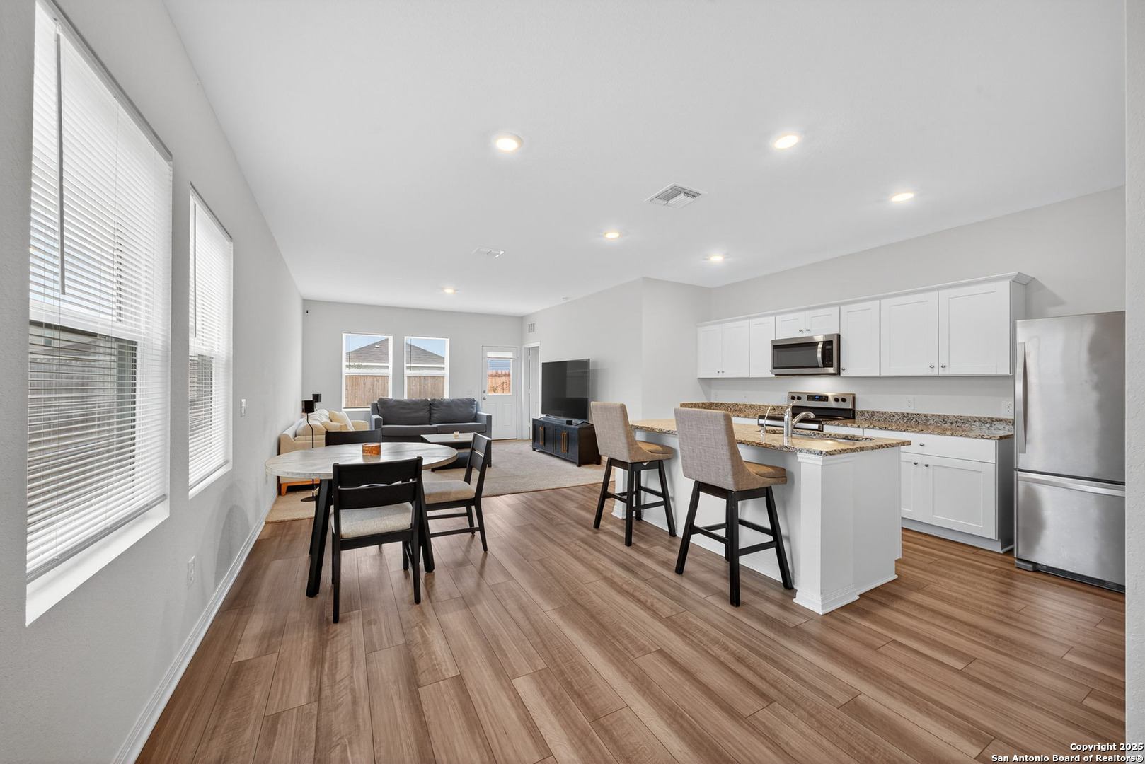 7710 Fern Hollow San Antonio, TX 78252 - Photo 5 of 26 a kitchen with a dining table chairs refrigerator microwave and cabinets