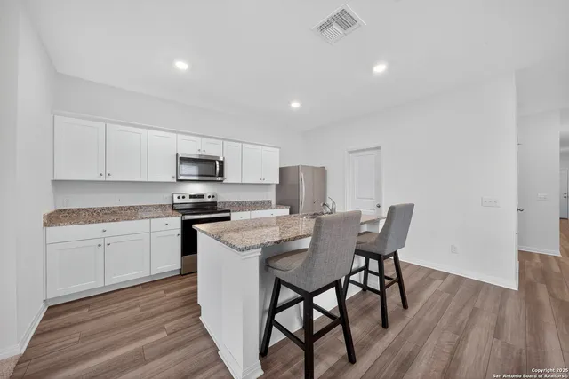 a kitchen with a table chairs a sink dishwasher a stove and cabinets with wooden floor