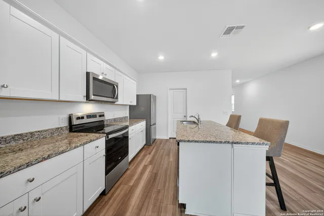 a kitchen with stainless steel appliances granite countertop a sink dishwasher stove top oven and refrigerator