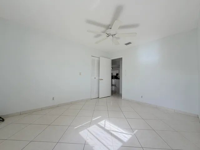 an empty room with a ceiling fan and window