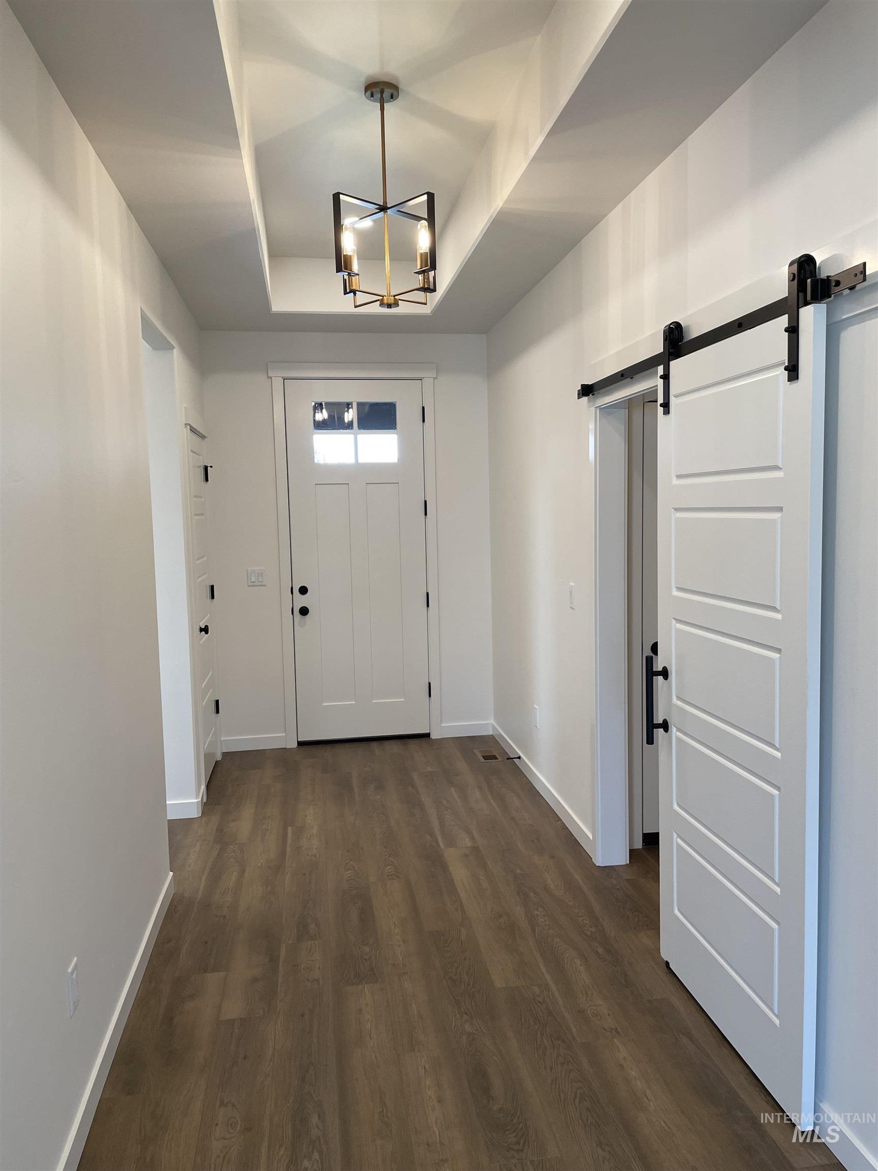 916 Kenbrook Loop Twin Falls, ID 83301 - Photo 14 of 30 Entrance foyer with a barn door, a chandelier, dark wood finished floors, and a raised ceiling