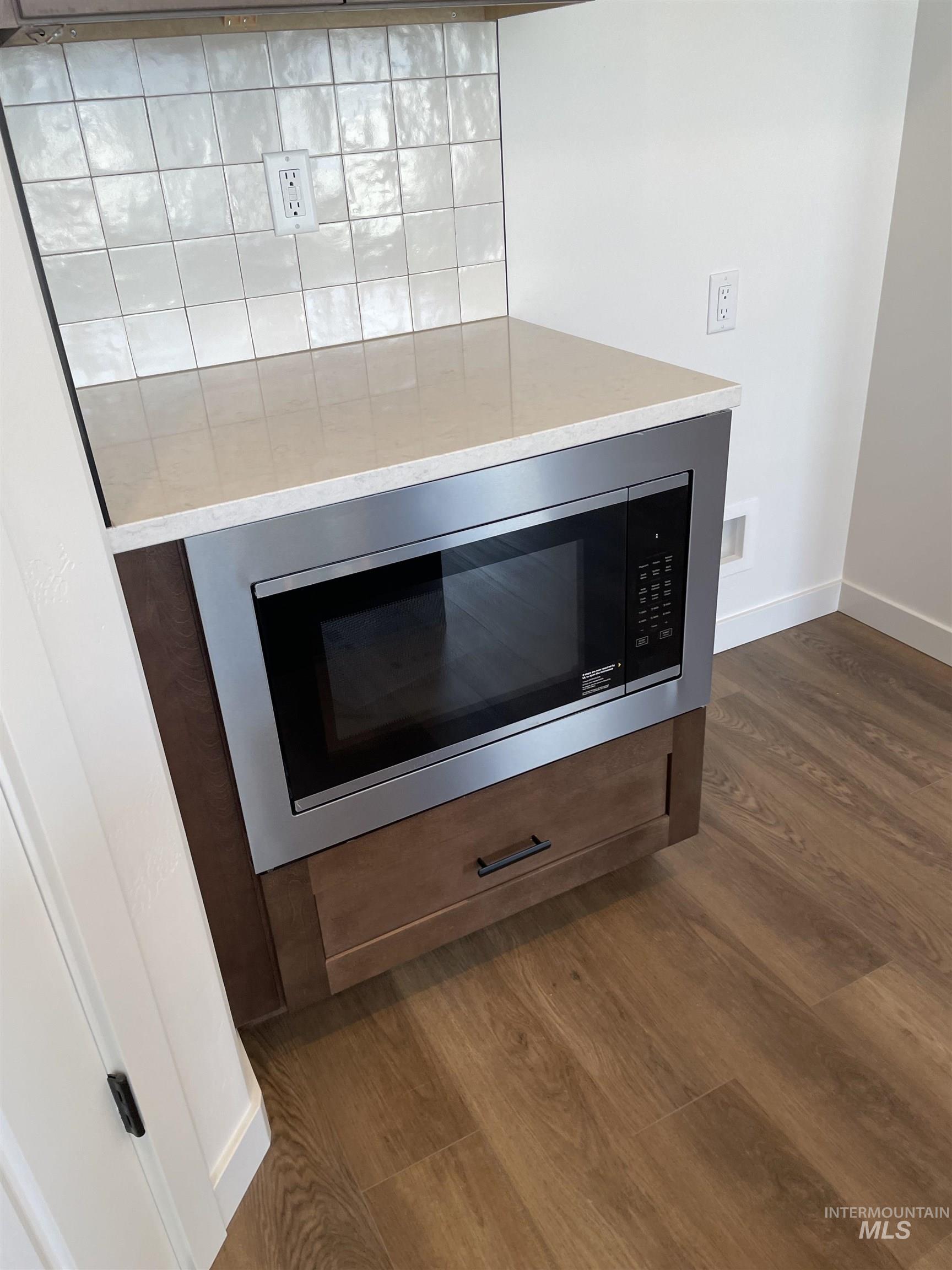 916 Kenbrook Loop Twin Falls, ID 83301 - Photo 7 of 30 Kitchen view of built in microwave, dark wood-style flooring, and light stone countertops