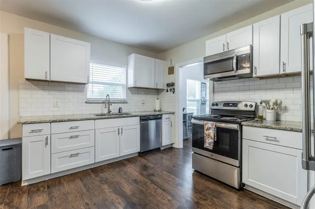 a kitchen with stainless steel appliances granite countertop a stove a sink and a microwave