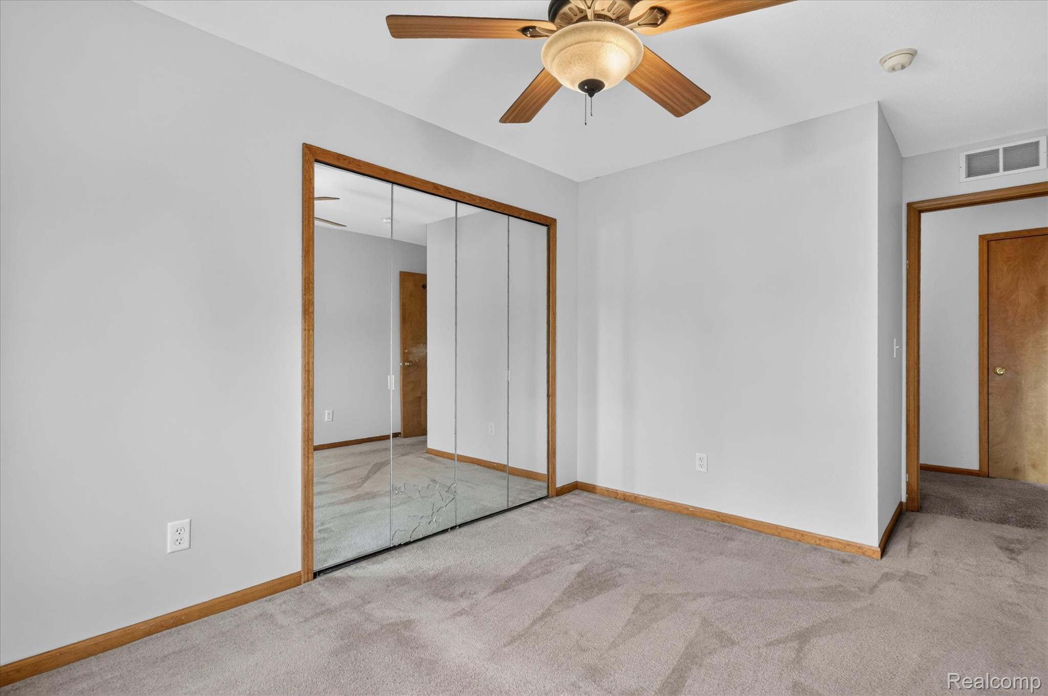 45720 Prairiegrass Court Belleville, MI 48111 - Photo 17 of 31 Bedroom featuring a full mirrored closet, light gray carpet flooring, and a ceiling fan with wood-finish blades