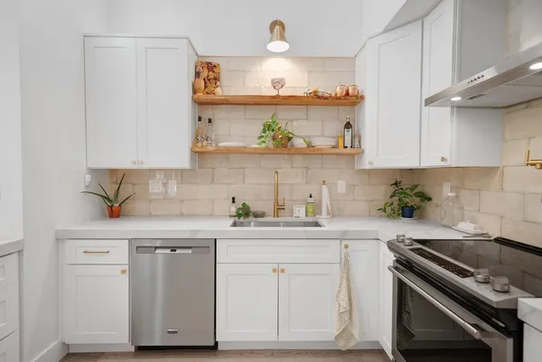 a kitchen with stainless steel appliances a sink a stove and cabinets