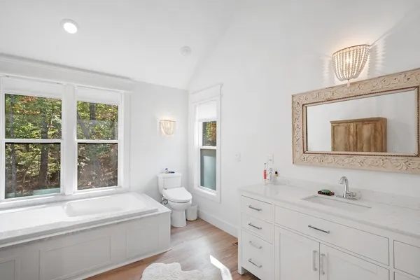 a bathroom with a granite countertop sink mirror bathtub and toilet