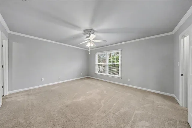 an empty room with windows and a chandelier fan