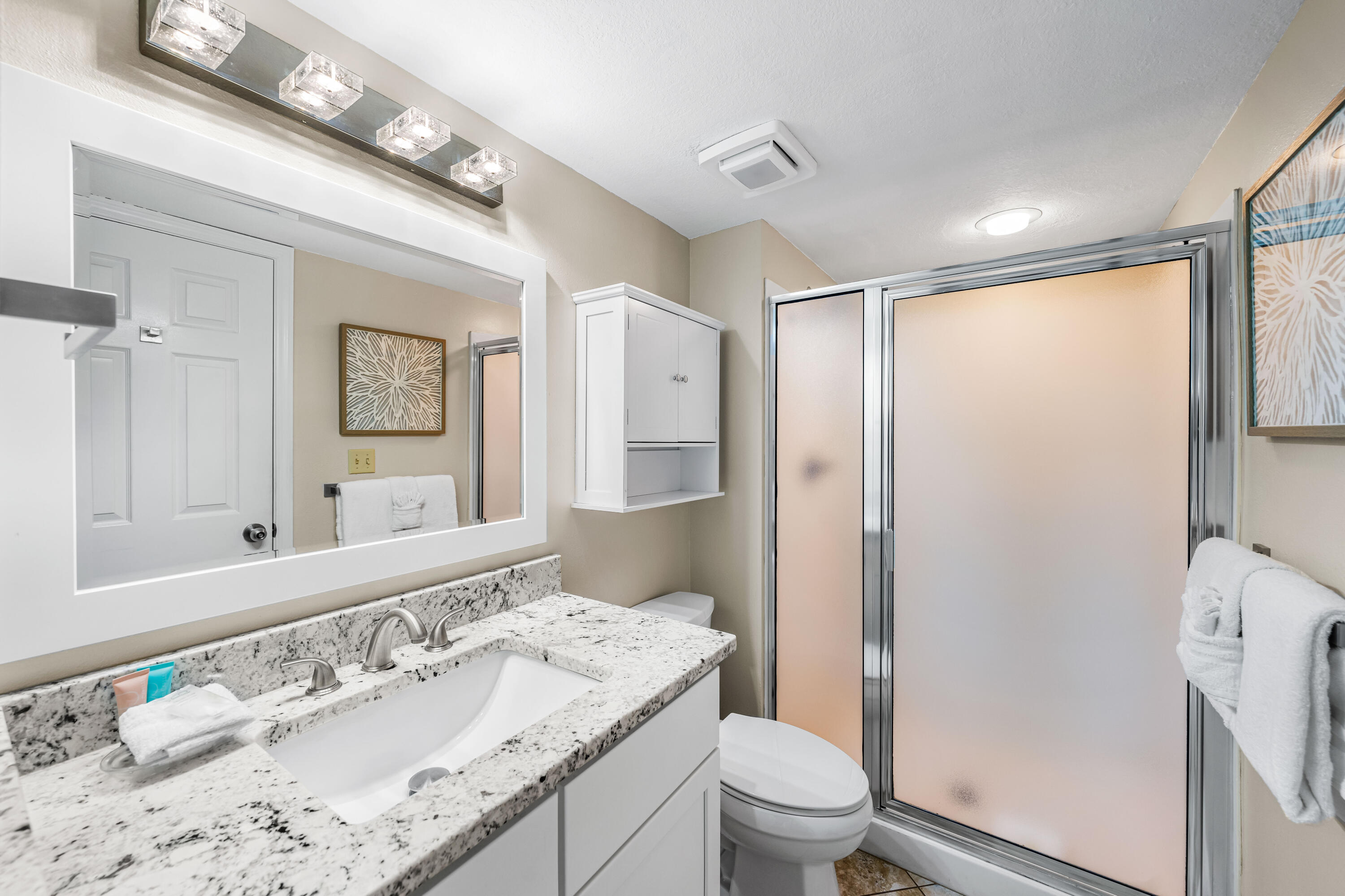 1002 Highway 98, Unit 415 Destin, FL 32541 - Photo 15 of 31 a bathroom with a granite countertop sink a toilet a mirror and shower