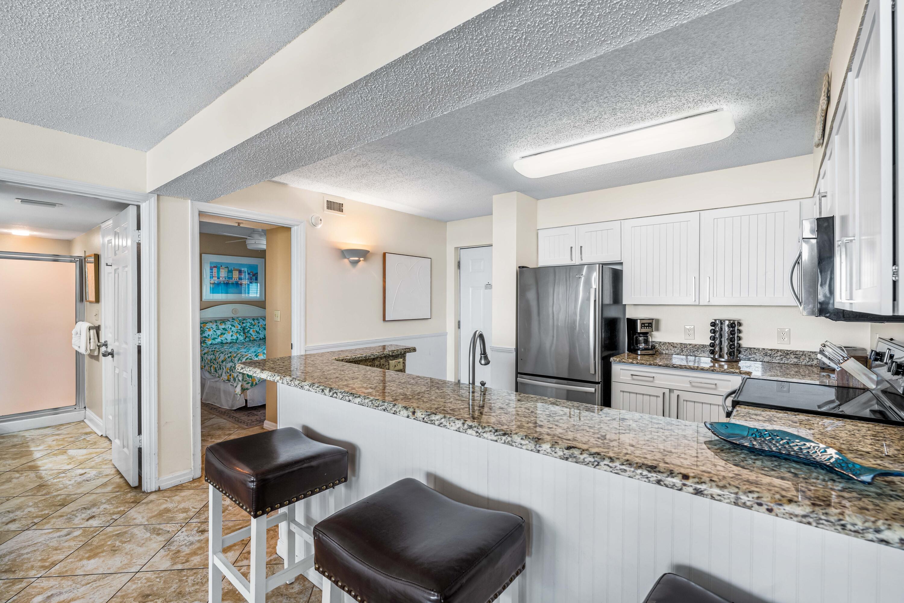 1002 Highway 98, Unit 415 Destin, FL 32541 - Photo 5 of 31 a large kitchen with granite countertop a refrigerator a sink a stove a dining table and chairs