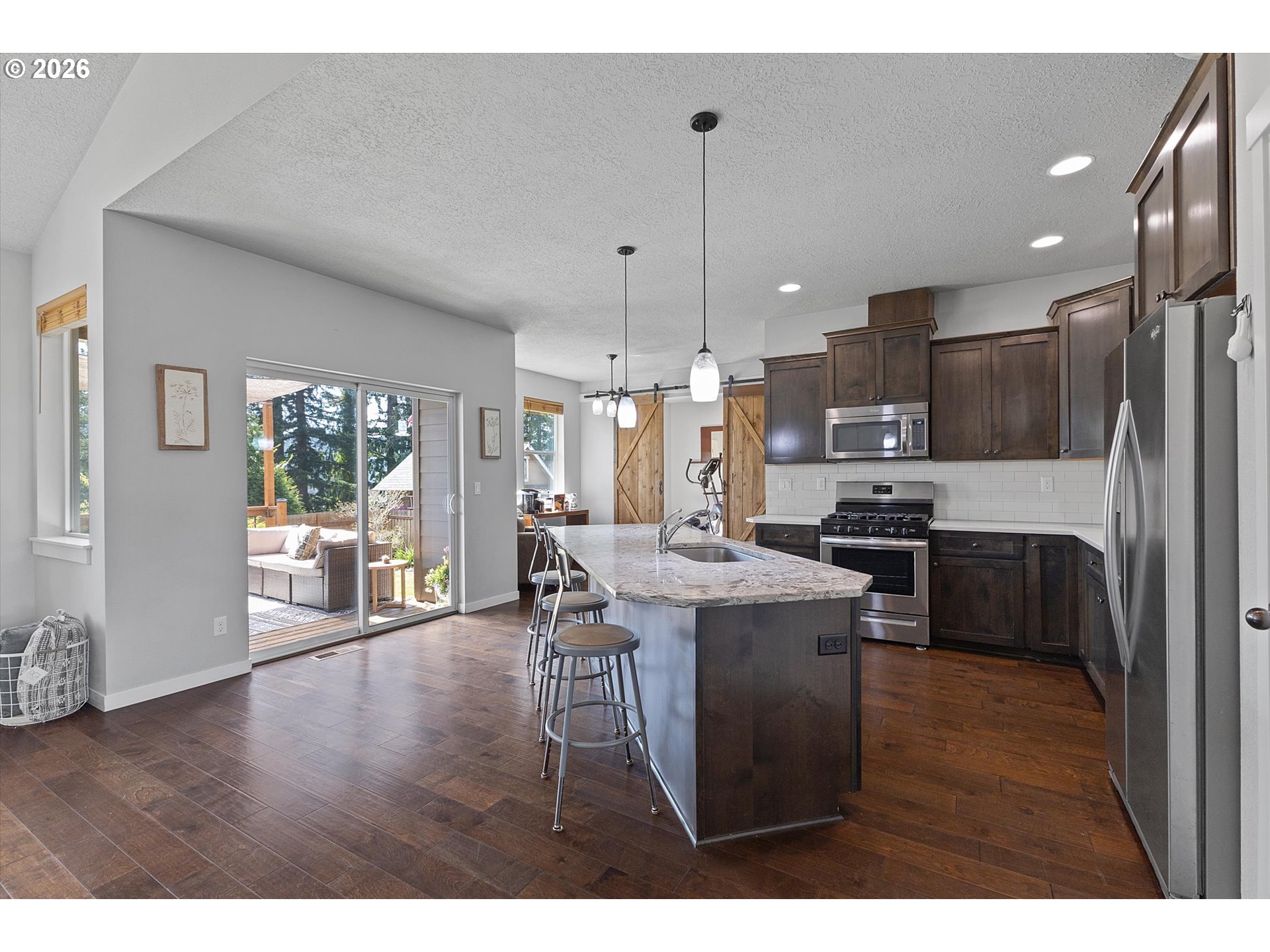 830 Southeast Darrow Road Estacada, OR 97023 - Photo 9 of 45 a kitchen with stainless steel appliances kitchen island granite countertop a stove a refrigerator a sink a dining table and chairs with wooden floor