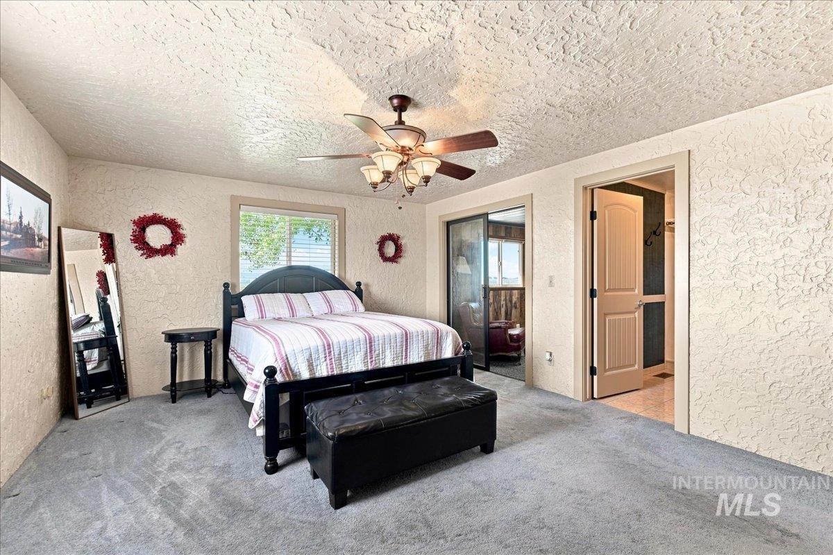 26201 Hop Road Caldwell, ID 83607 - Photo 17 of 45 Neutral-toned walls with texture, light gray carpeting, and a ceiling fan with integrated lighting