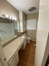 1400 Fairground Street, Unit C Taylor, TX 76574 - Photo 11 of 12 a bathroom with a granite countertop sink a toilet and a mirror