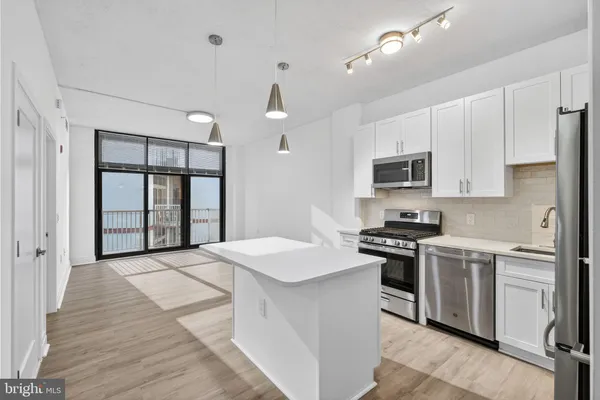 a kitchen with stainless steel appliances granite countertop a stove top oven a sink dishwasher a refrigerator and white cabinets with wooden floor