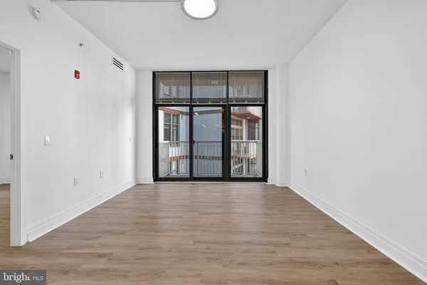 a view of an empty room with a window and wooden floor