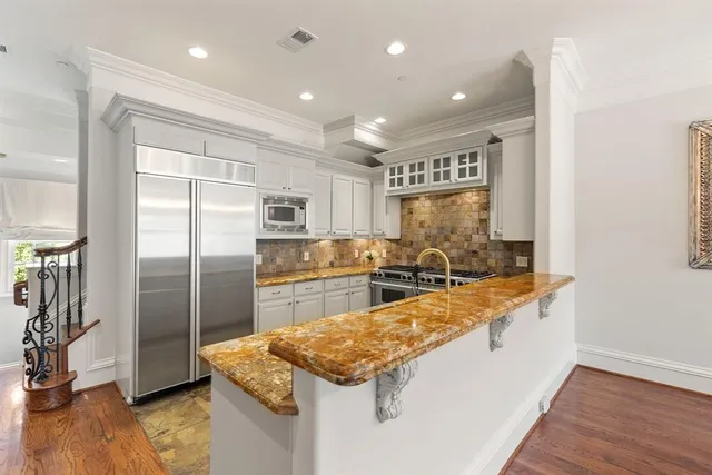 a large kitchen with stainless steel appliances granite countertop a sink and a refrigerator