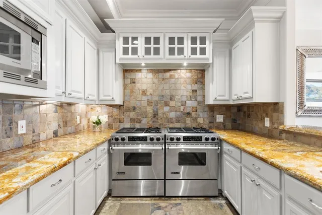 a white kitchen with granite countertop stainless steel appliances
