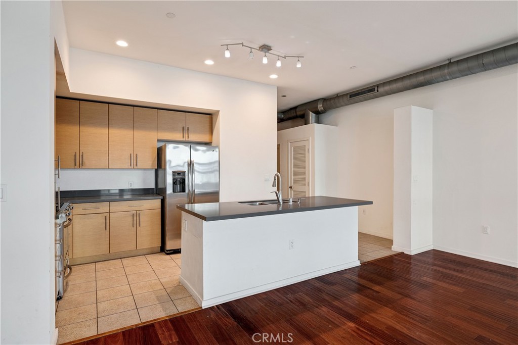 133 The Promenade North, Unit 426 Long Beach, CA 90802 - Photo 14 of 57 a large kitchen with stainless steel appliances granite countertop a sink and dishwasher with wooden floor