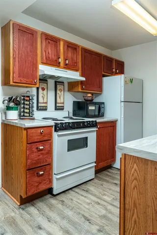 a kitchen with stainless steel appliances granite countertop a stove a sink dishwasher and a refrigerator with wooden cabinets