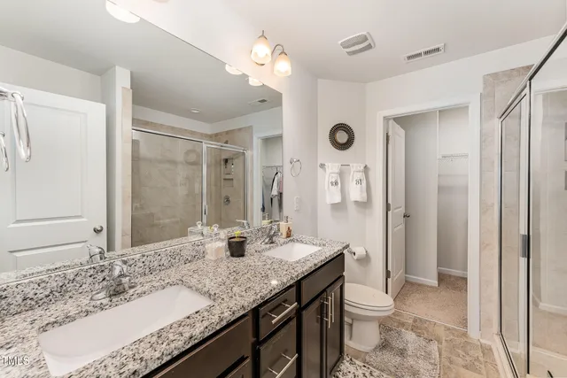 a bathroom with a granite countertop sink a toilet a large mirror and shower