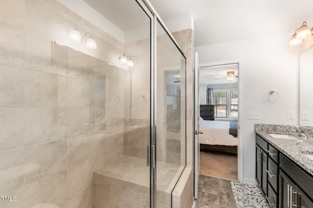 a en suite bathroom with a granite countertop sink a mirror and shower
