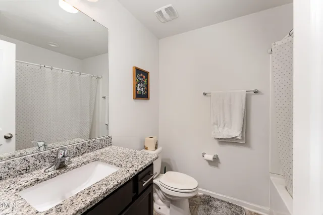 a bathroom with a granite countertop sink and a mirror with toilet