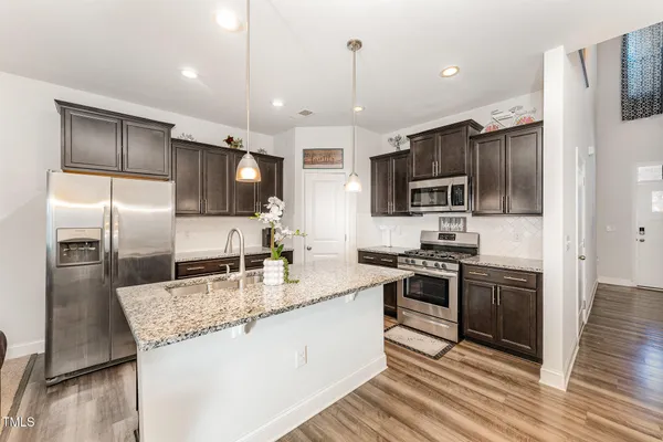 a large kitchen with granite countertop a large counter top stainless steel appliances and wooden floor
