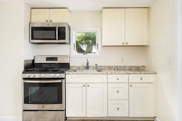 a kitchen with granite countertop white cabinets and stainless steel appliances