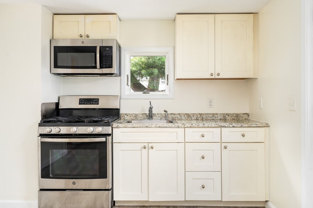 111 Washington Street, Unit 2 Somerville, MA 02145 - Photo 2 of 14 a kitchen with granite countertop white cabinets and stainless steel appliances