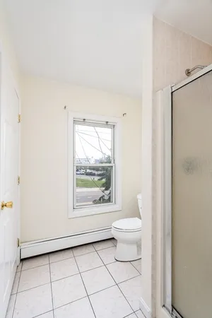 a bathroom with a toilet a window and a shower