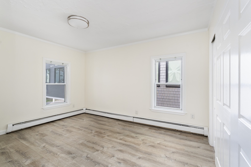 111 Washington Street, Unit 2 Somerville, MA 02145 - Photo 5 of 14 an empty room with wooden floor and windows