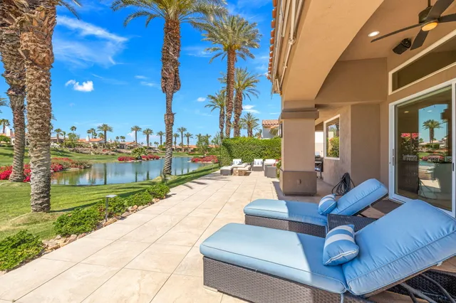 a view of a patio with couches and table and chairs next to yard with wooden fence