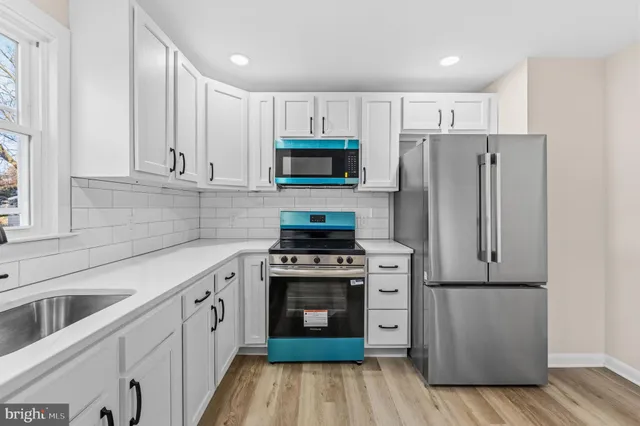 a kitchen with cabinets stainless steel appliances and wooden floor