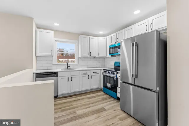 a kitchen with a refrigerator stainless steel appliances wooden floor and cabinets