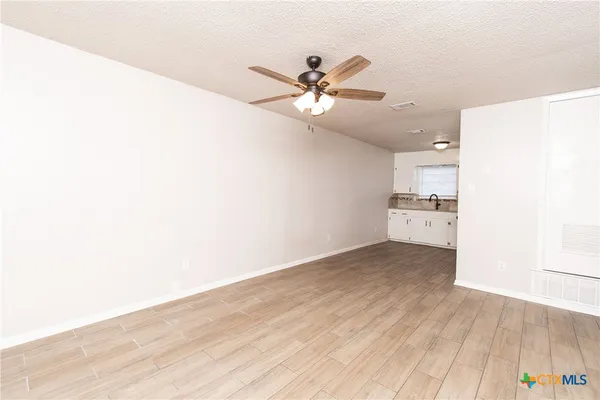 a view of a kitchen with wooden floor and a ceiling fan