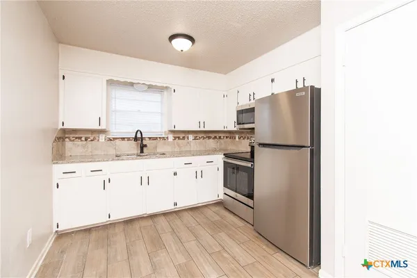 a kitchen with granite countertop white cabinets and white appliances