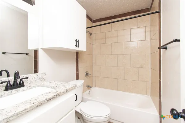 a bathroom with a granite countertop sink toilet mirror and bathtub