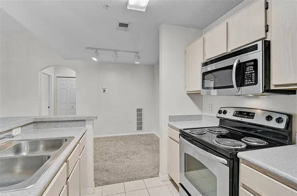 a kitchen with granite countertop a sink dishwasher stove and microwave with wooden cabinets