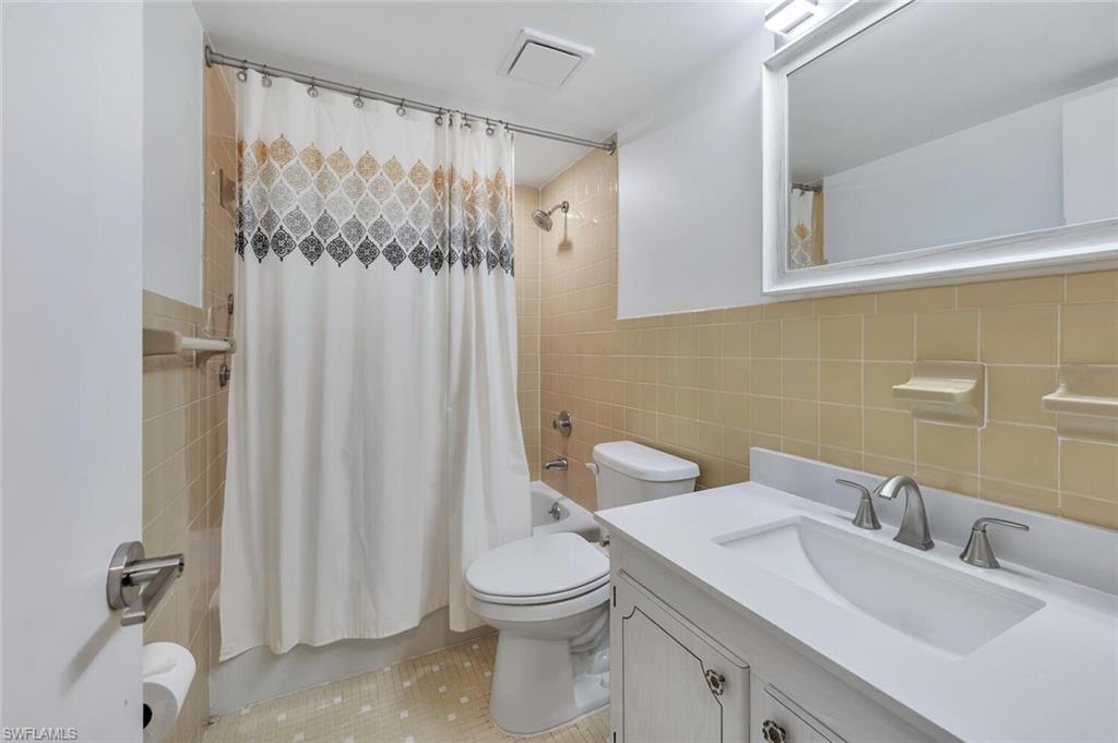 3030 Binnacle Drive, Unit 201 Naples, FL 34103 - Photo 9 of 16 a bathroom with a toilet a sink and a mirror