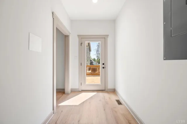 a view of a hallway with wooden floor and a bathroom