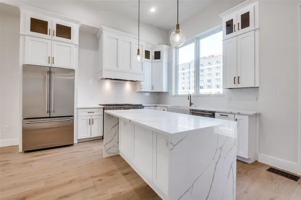 a kitchen with kitchen island a sink a stove a refrigerator and white cabinets