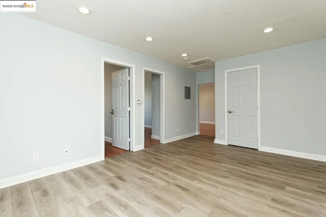 an empty room with wooden floor & closet area