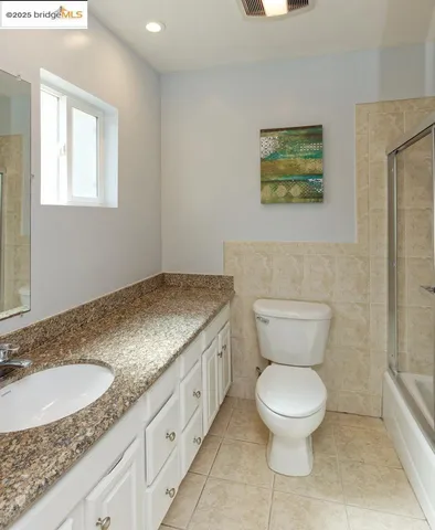 a bathroom with a granite countertop toilet sink and mirror