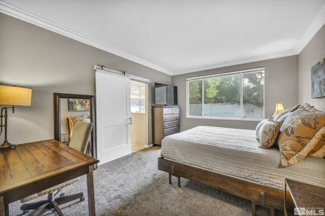 a bedroom with a bed and a flat tv screen next to a window