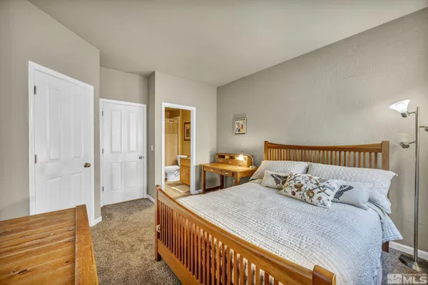 a bed sitting in a bedroom and table next to a window