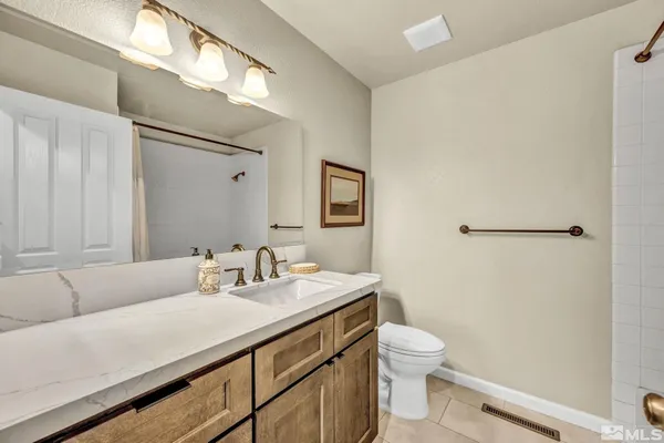 a bathroom with a granite countertop sink a toilet and a mirror
