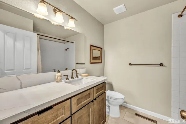a bathroom with a granite countertop sink a toilet and a mirror