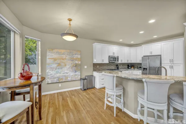 a kitchen with stainless steel appliances granite countertop a stove a refrigerator a kitchen island a dining table and chairs